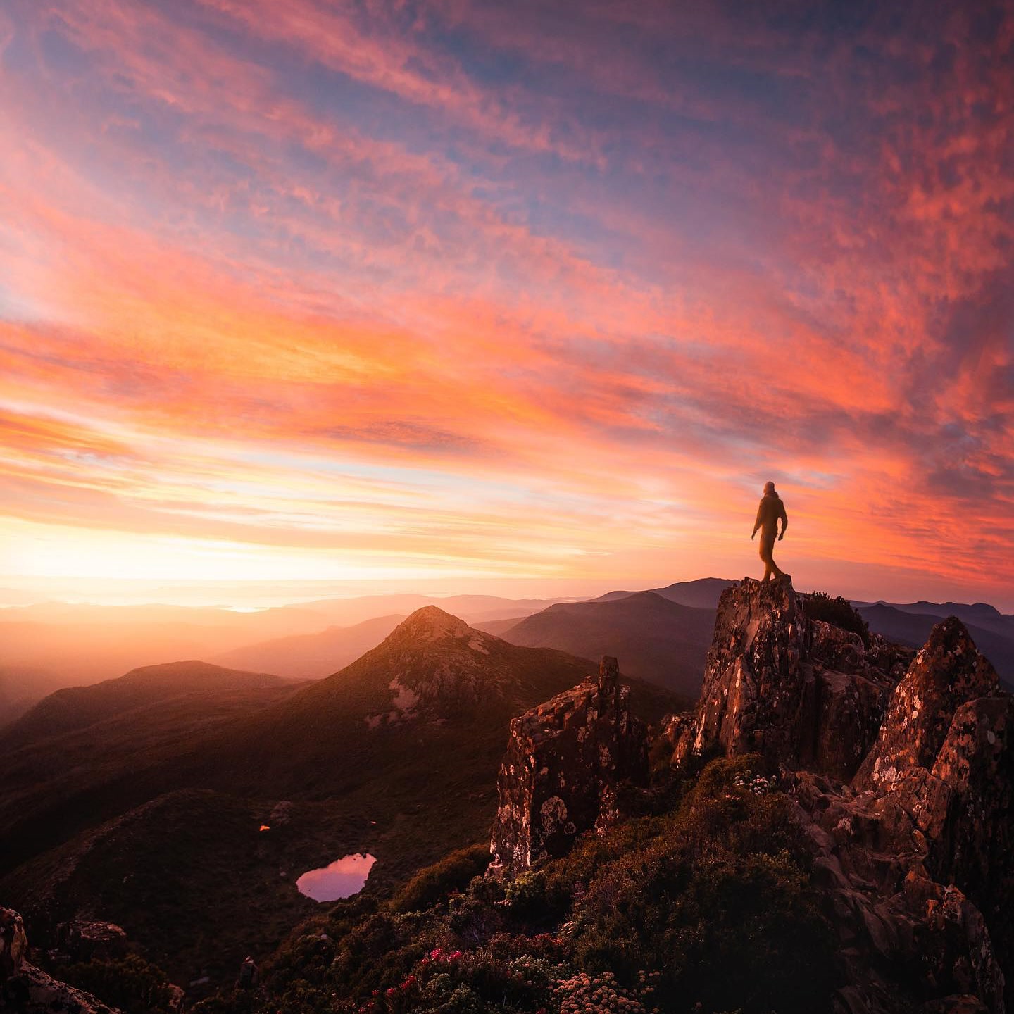 Hiker on Hartz Peak beneath a vivid sunrise sky